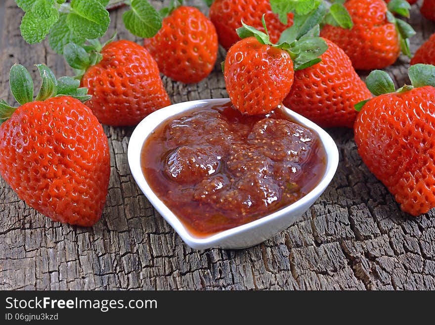 Strawberry jam and strawberry on a wooden surface