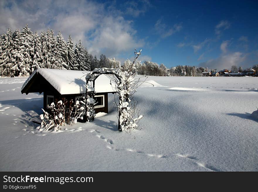 Snowy small wooden house, footprints in the snow. Snowy small wooden house, footprints in the snow