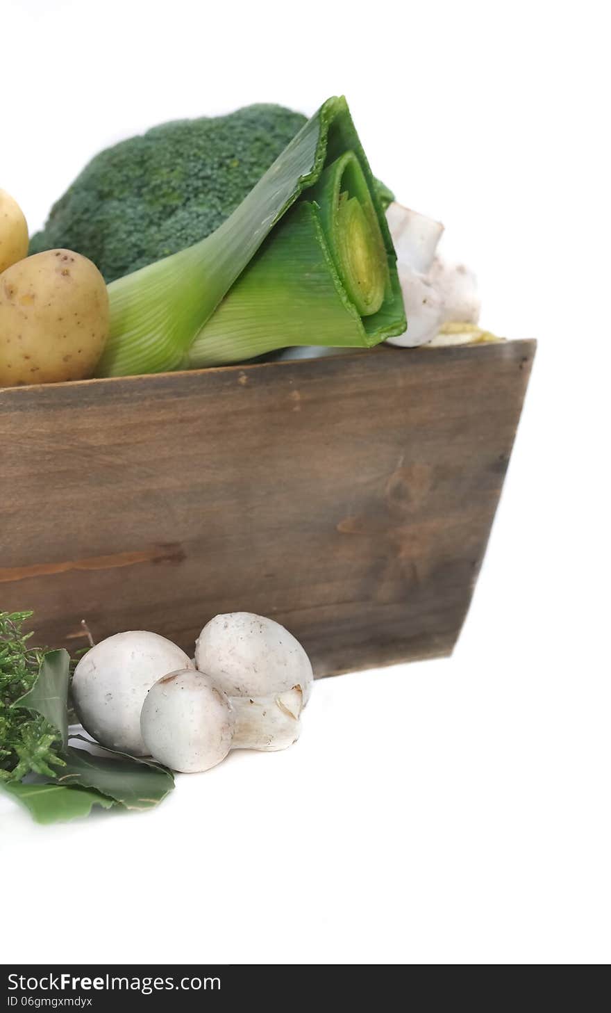 Different seasonal vegetables and mushrooms in wooden basket on white background