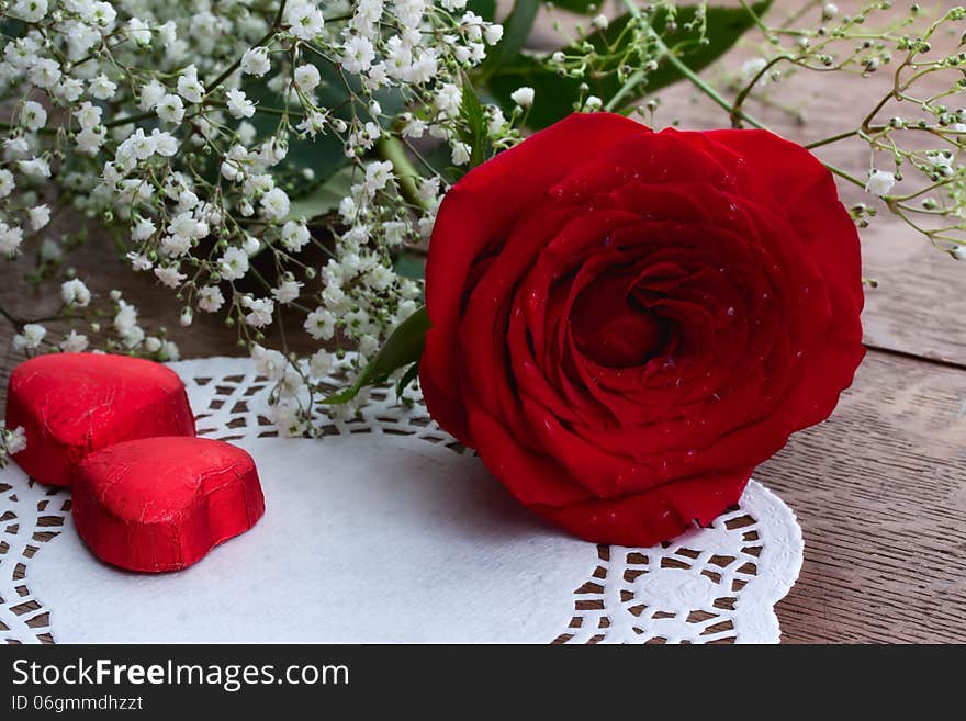 Red rose and chocolates wrapped in foil in the form of heart, as a greeting card