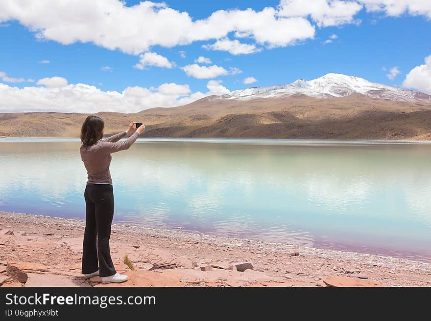 Woman taking pictures of lagoon Celeste, Bolivia on mobile phone. Woman taking pictures of lagoon Celeste, Bolivia on mobile phone