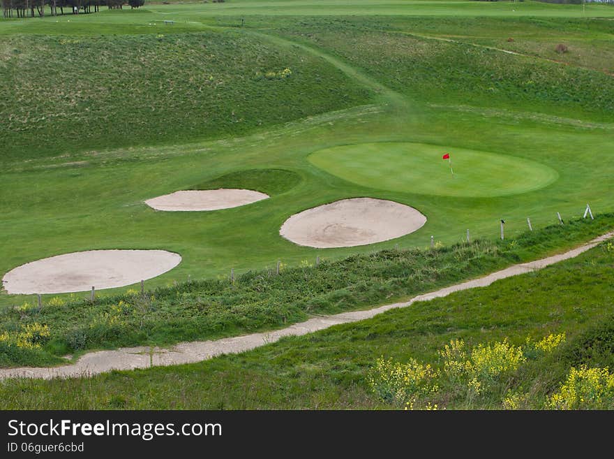 Wavy green golf field with a red flag