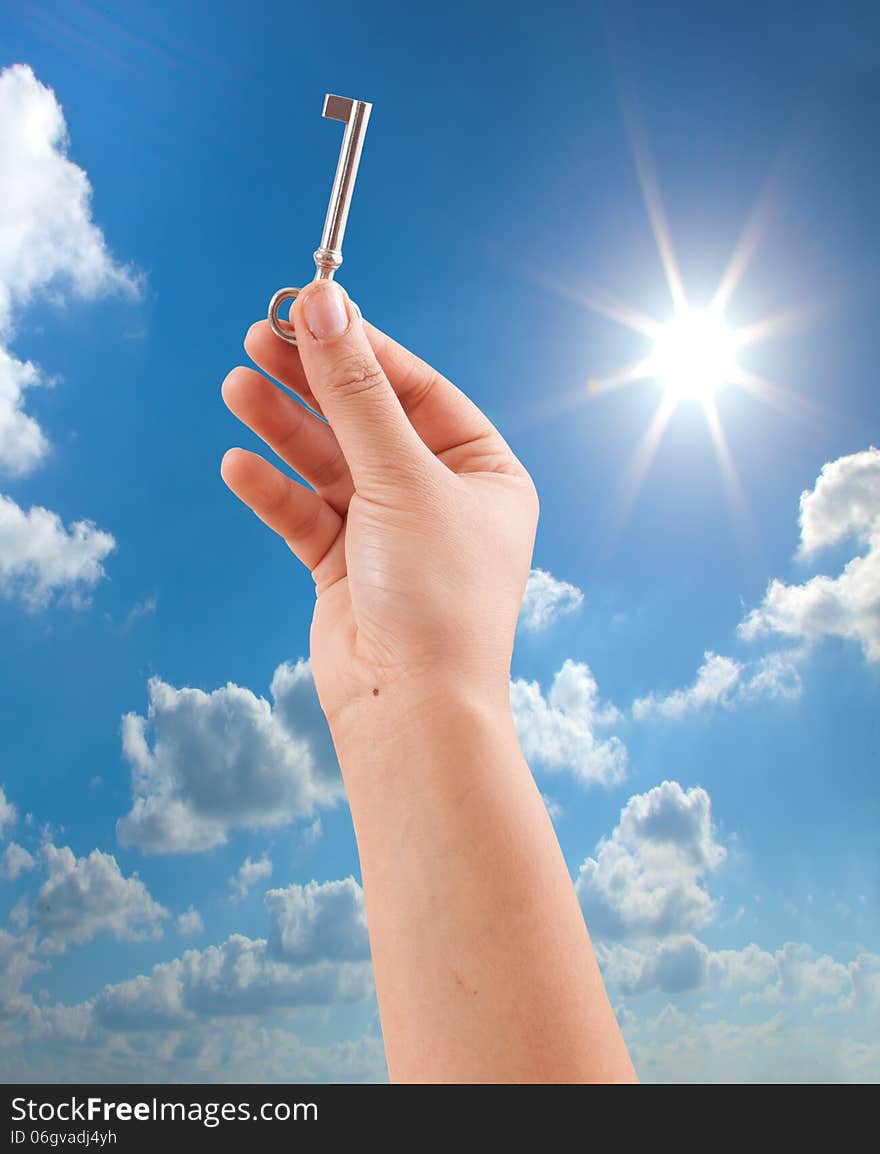 Hand holding key on sunny sky background