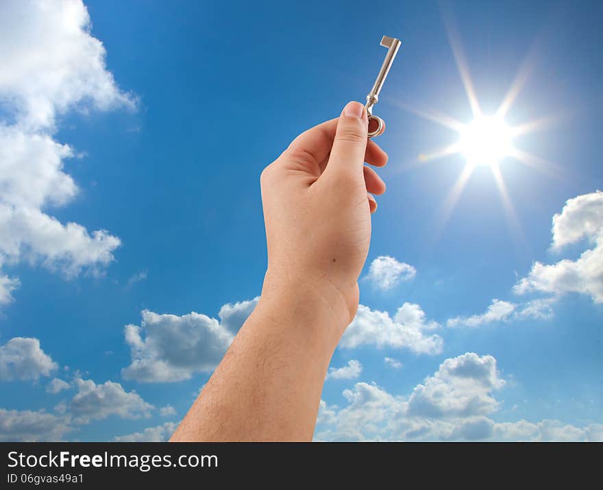 Hand holding key on sunny sky background. Hand holding key on sunny sky background