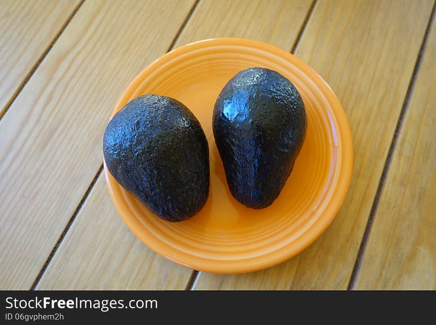 A picture of two avocado on a small plate. A picture of two avocado on a small plate.