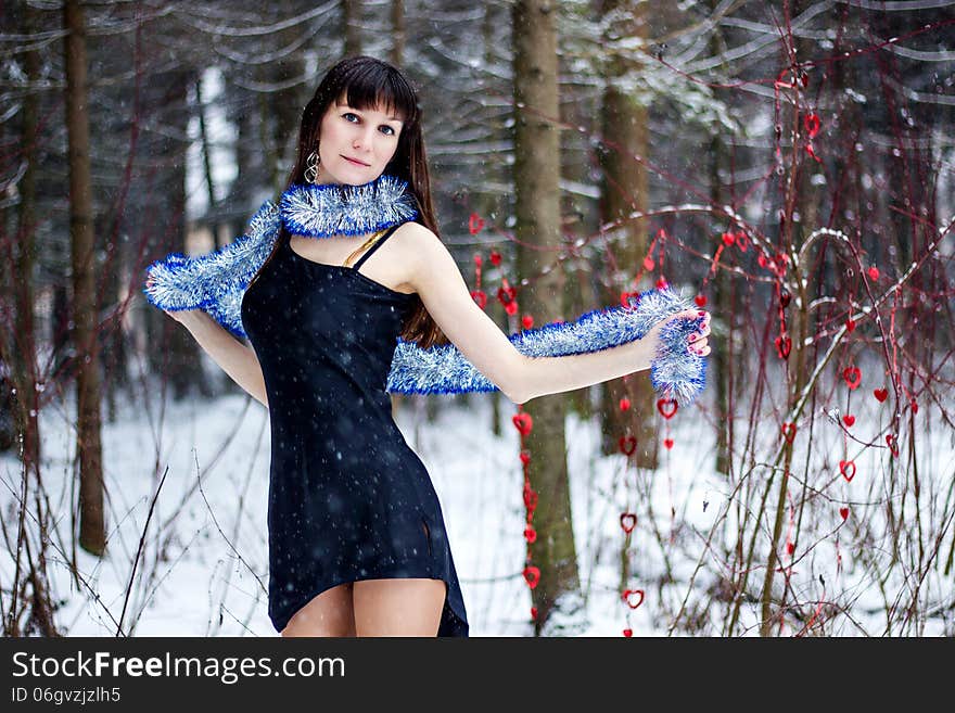 Beautiful woman with bright tinsel in winter forest