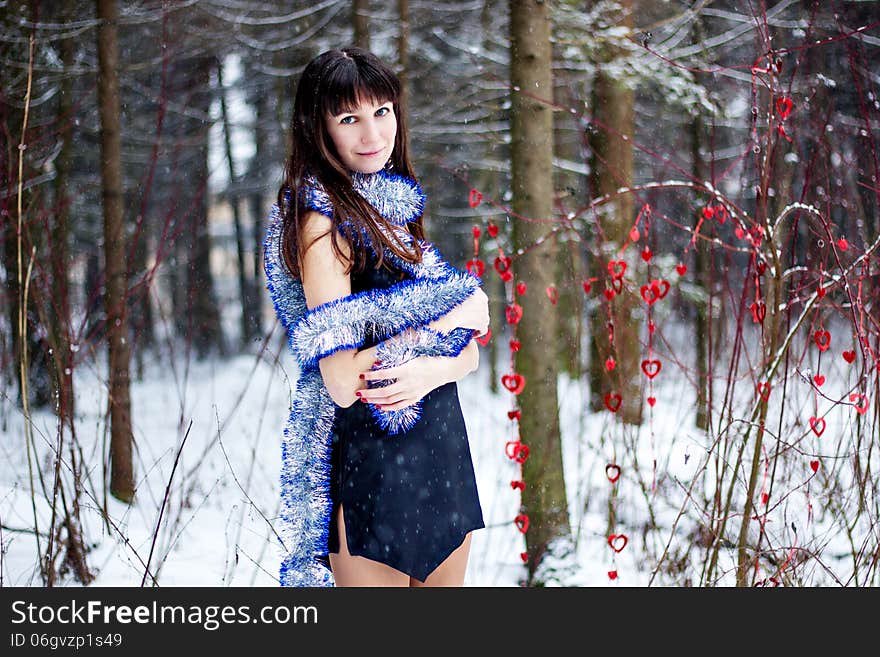 Beautiful woman with bright tinsel in winter forest