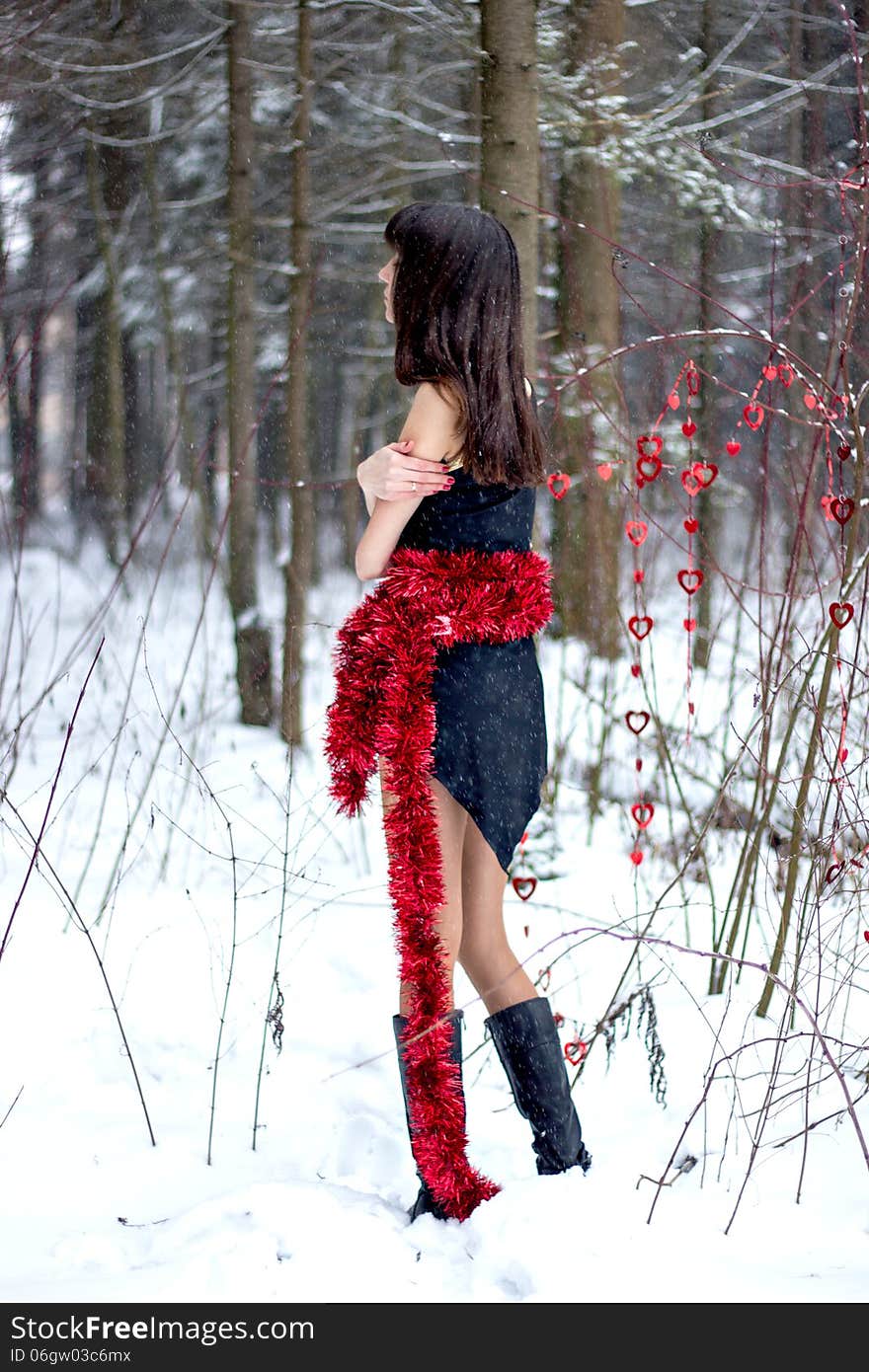 Beautiful woman with bright tinsel in winter forest