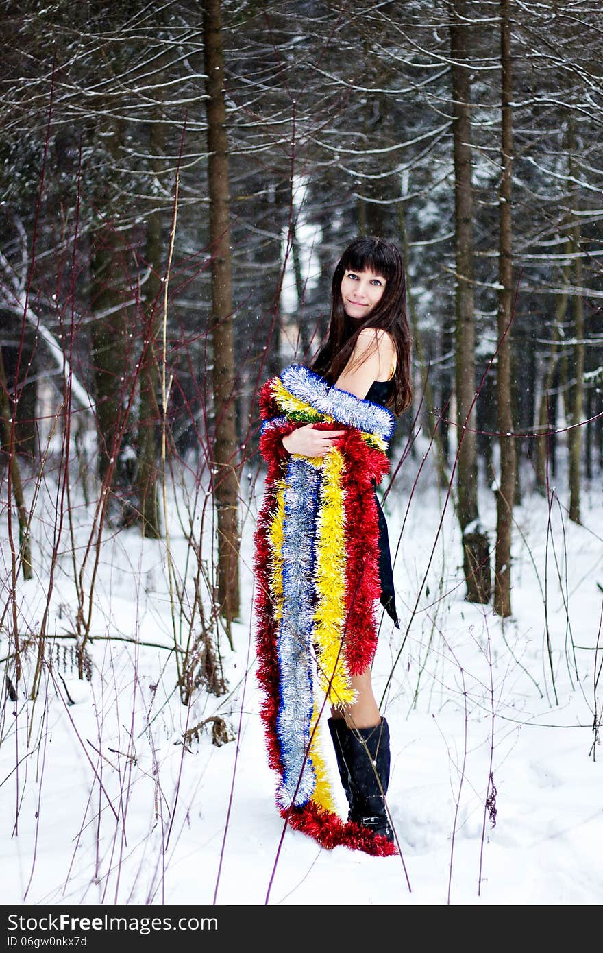 Beautiful woman with bright tinsel in winter forest