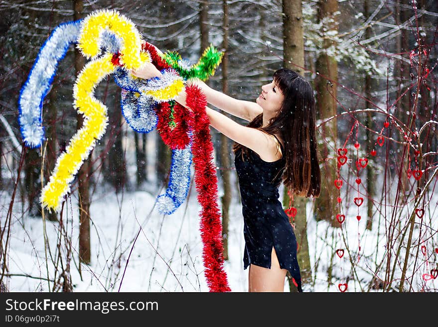 Beautiful woman with bright tinsel in winter forest