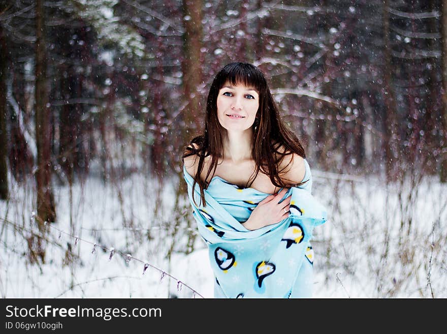 Beautiful woman under warm cute wrap in cold snow forest