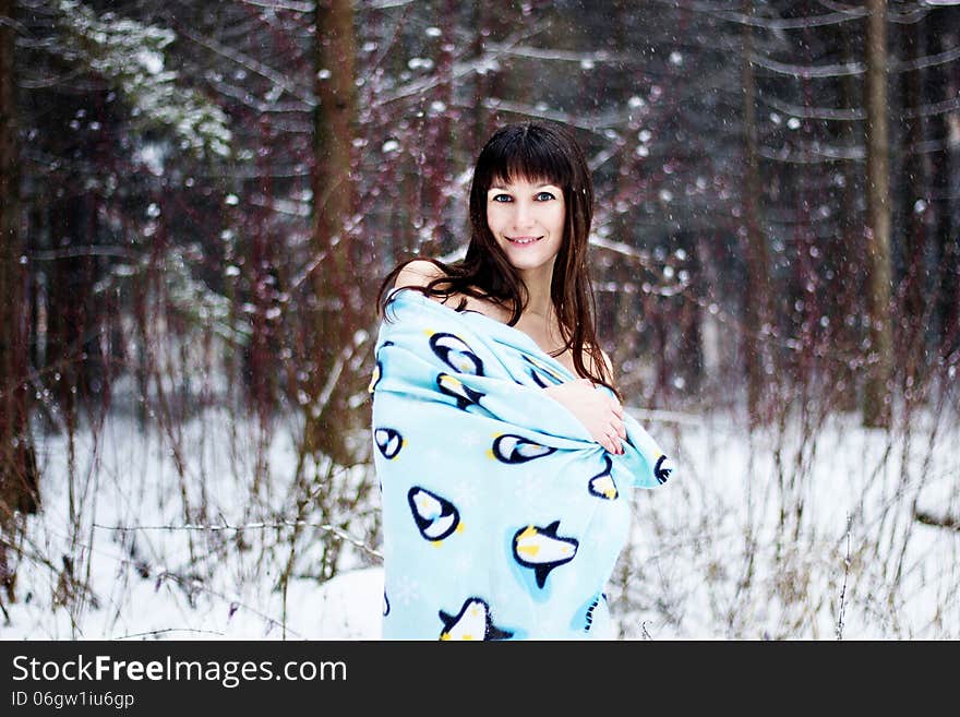 Beautiful woman under warm cute wrap in cold snow forest