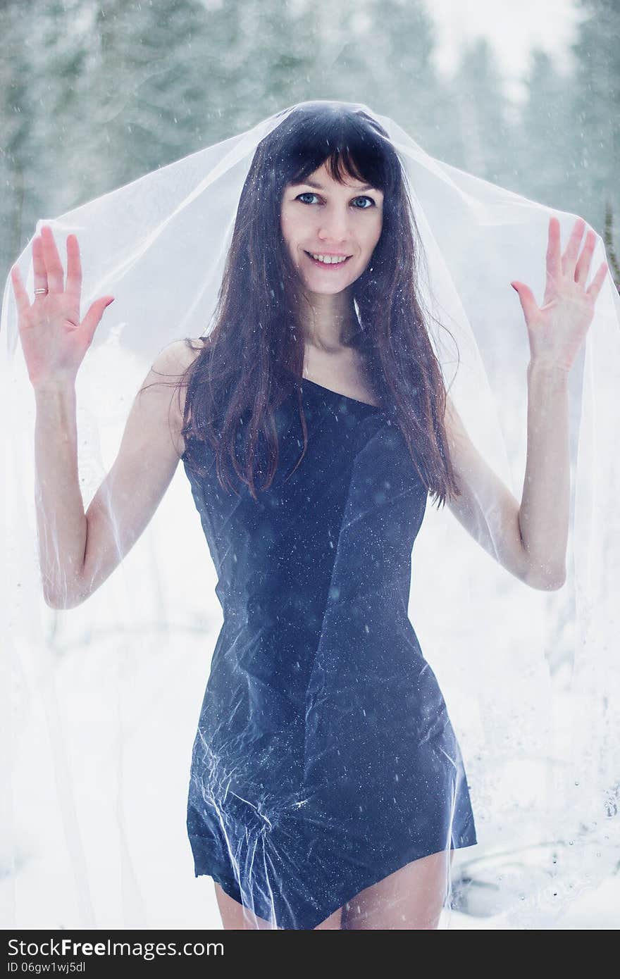 Beautiful bride under veil on white snow background