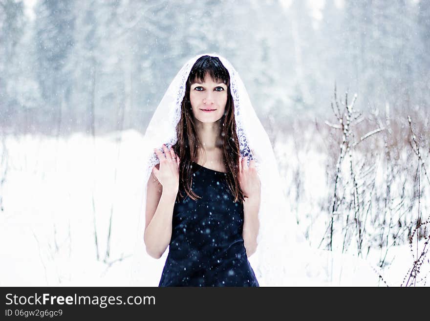 Beautiful bride under veil on white snow background