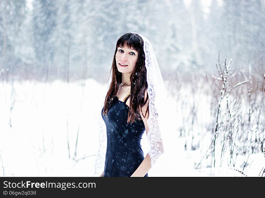 Beautiful bride under veil on white snow background