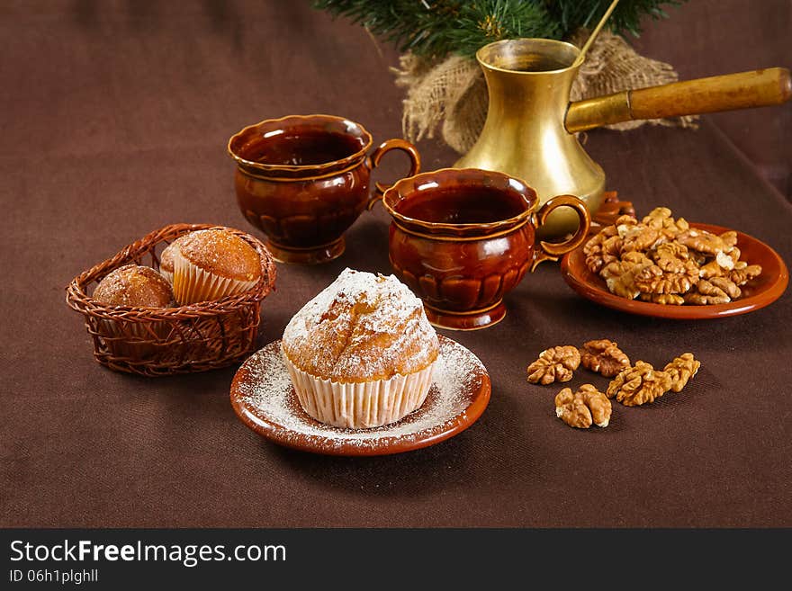 Fresh muffins on a brown table with a cups of coffee and coffee pot