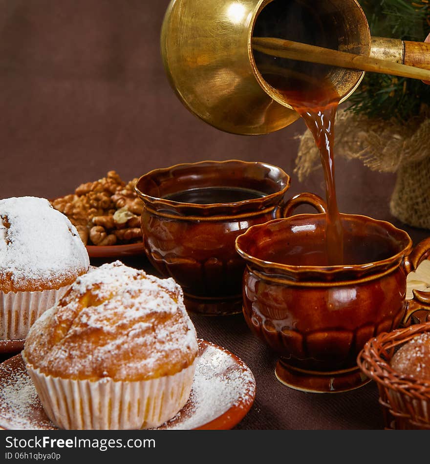 Fresh muffins on a brown table with a cups of coffee and coffee pot