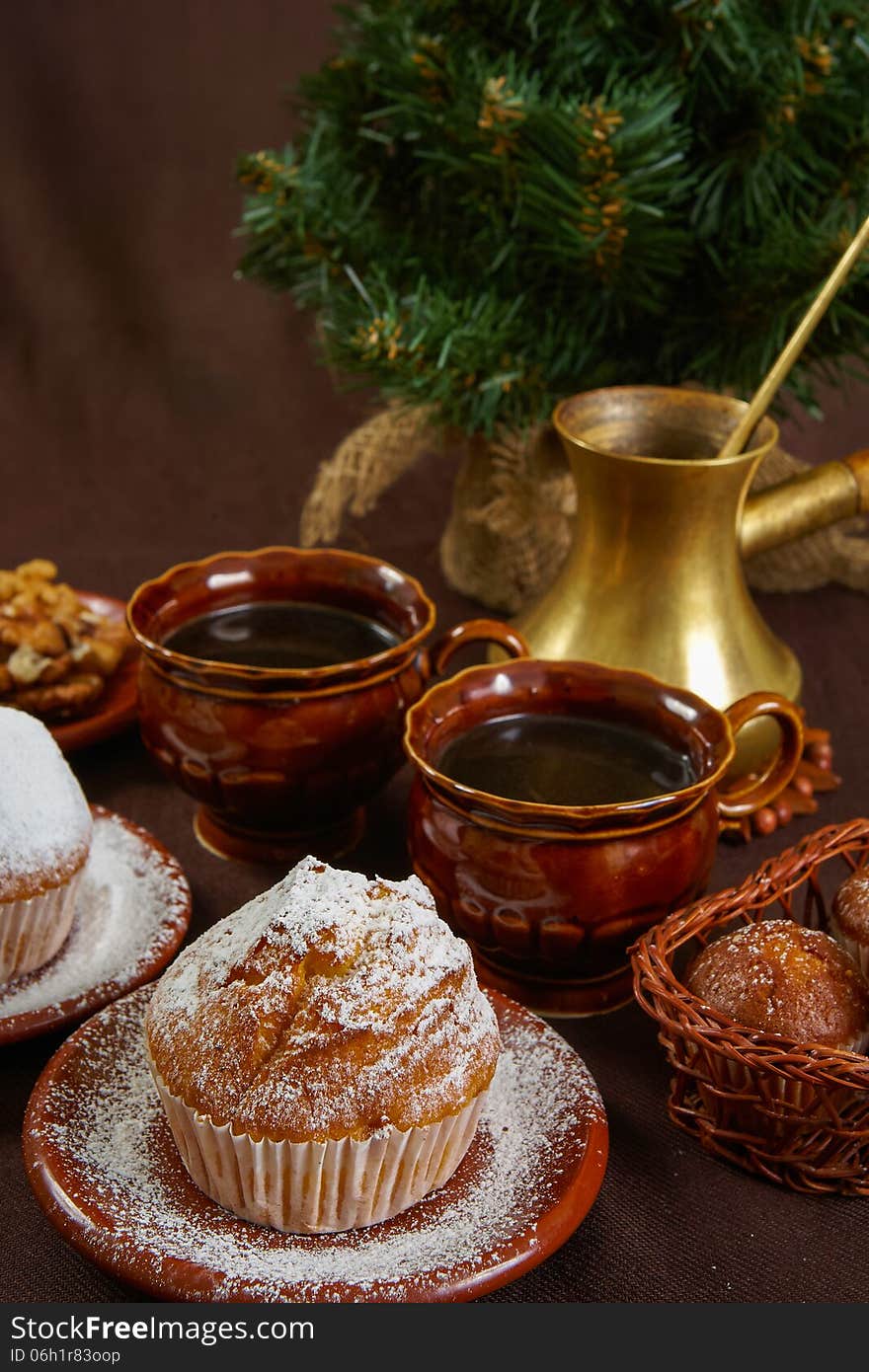 Fresh muffins on a brown table with a cups of coffee and coffee pot