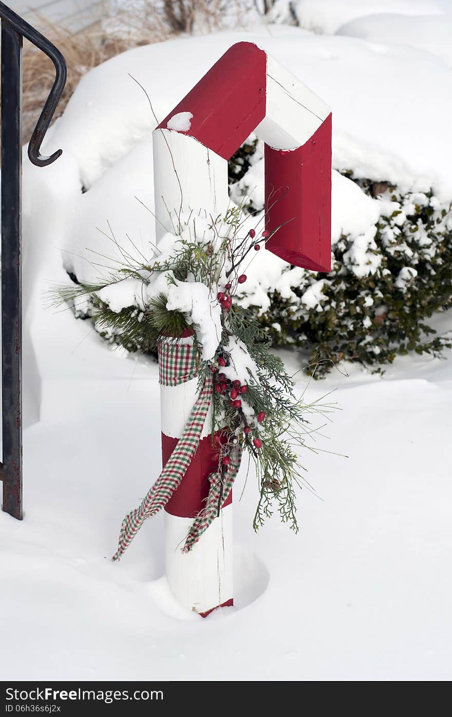 A large red and white candycane sits outside in winter. A large red and white candycane sits outside in winter.