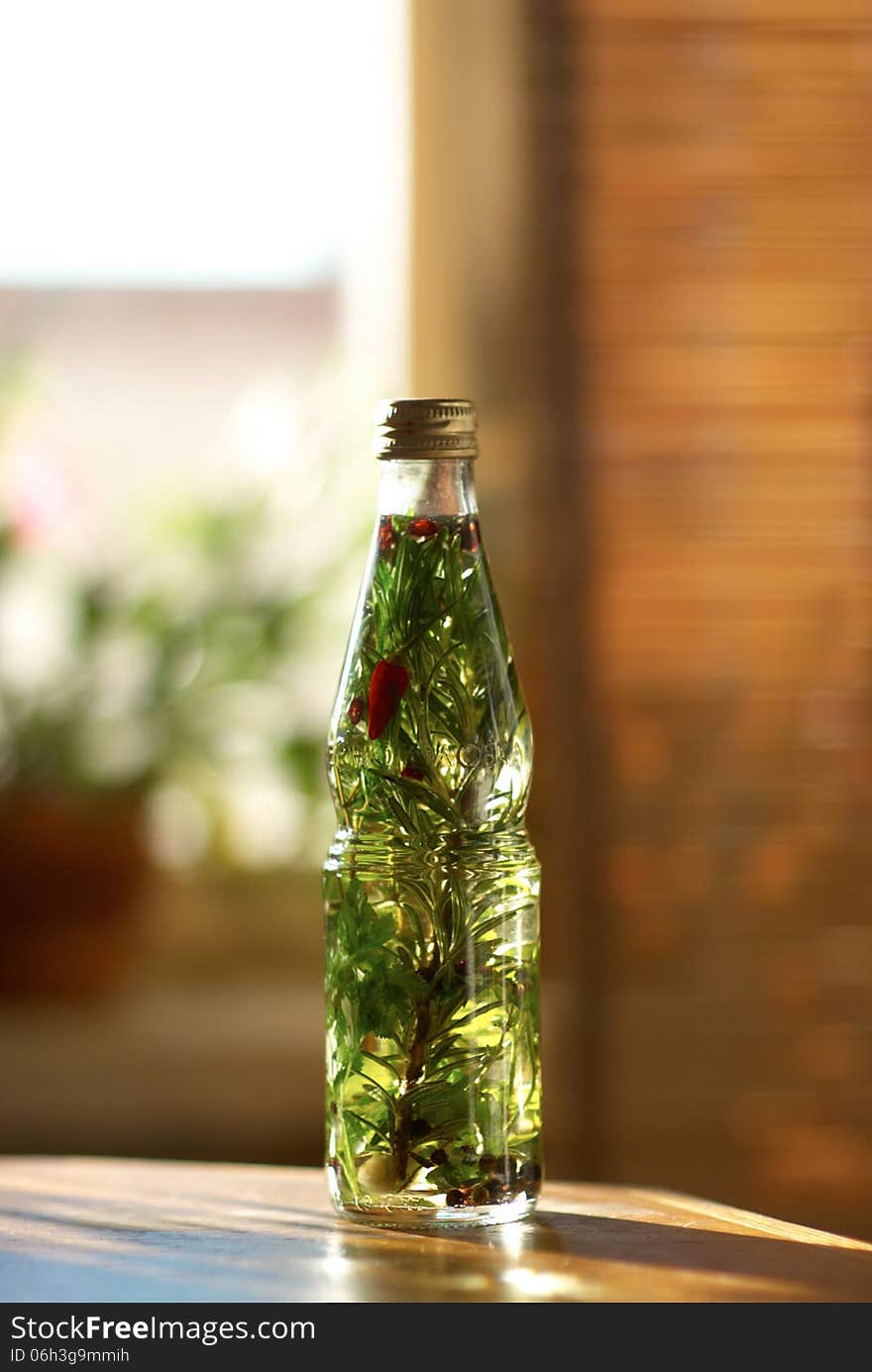 Bottle with herb oil, pepper and garlic on the table. Bottle with herb oil, pepper and garlic on the table