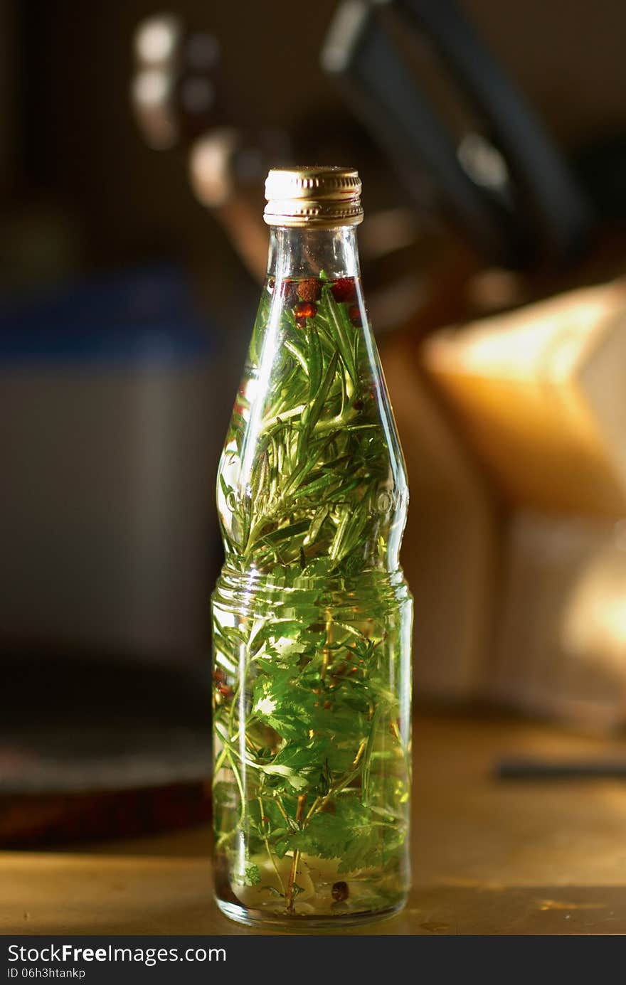 Bottle with herb oil, pepper and garlic on the table. Bottle with herb oil, pepper and garlic on the table