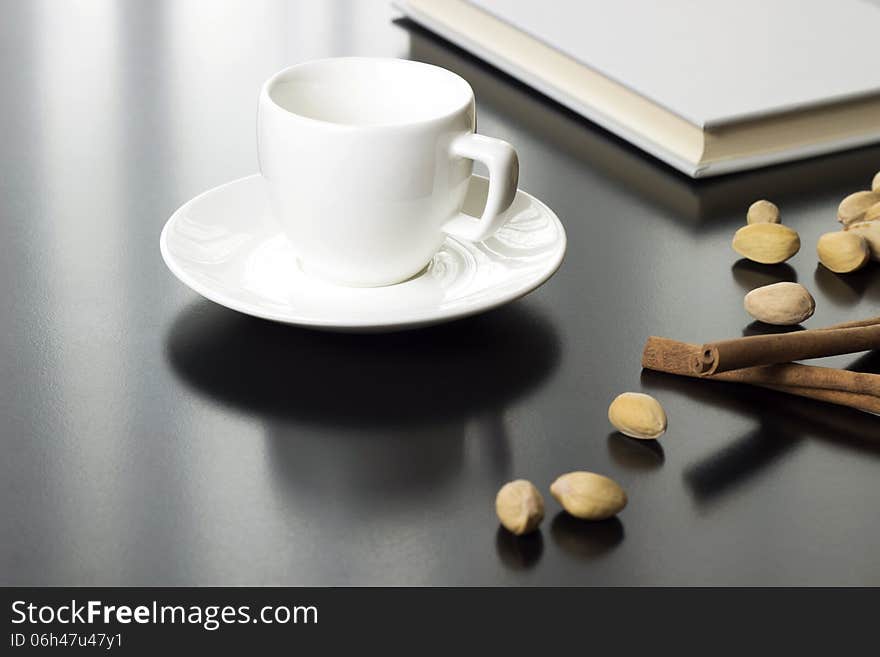 Cup of coffee and closed book on table with nuts and cinnamon. Cup of coffee and closed book on table with nuts and cinnamon