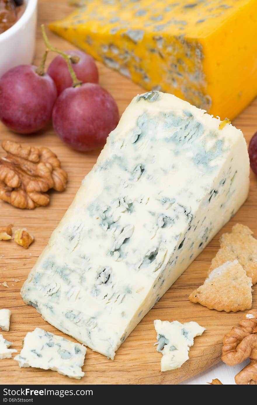 Blue cheese, grapes, crackers, jam and nuts on a wooden board, vertical