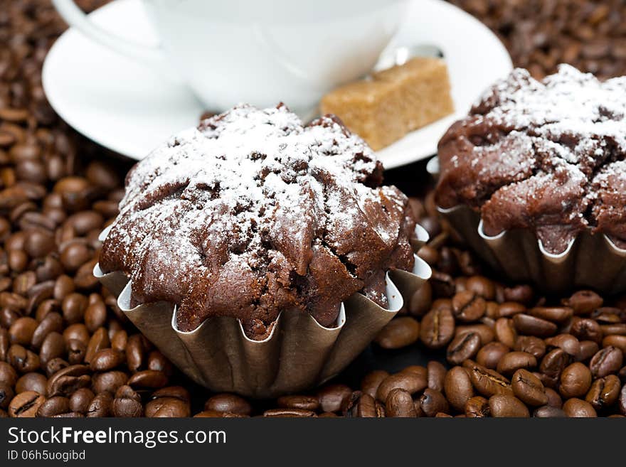 Chocolate muffin and cappuccino on coffee beans, close-up