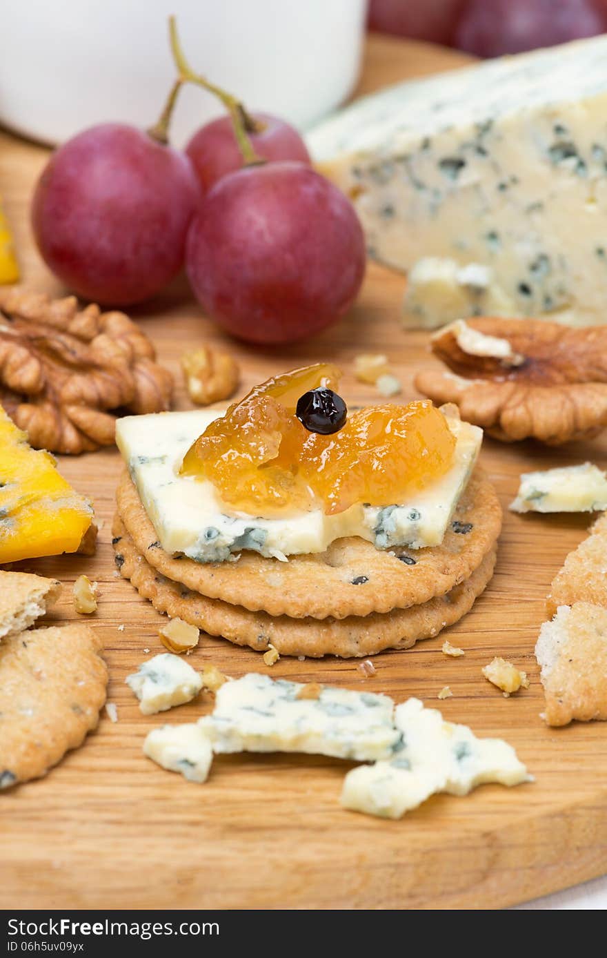 Crackers with blue cheese and apple jam, nuts and grapes, vertical, close-up