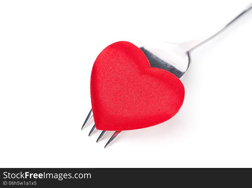 Red heart on a fork, close-up, isolated on white