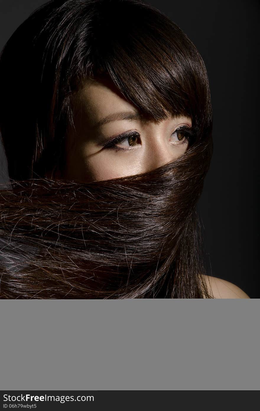 Asian lady masking the lower potion of her face with her own hair. Asian lady masking the lower potion of her face with her own hair.