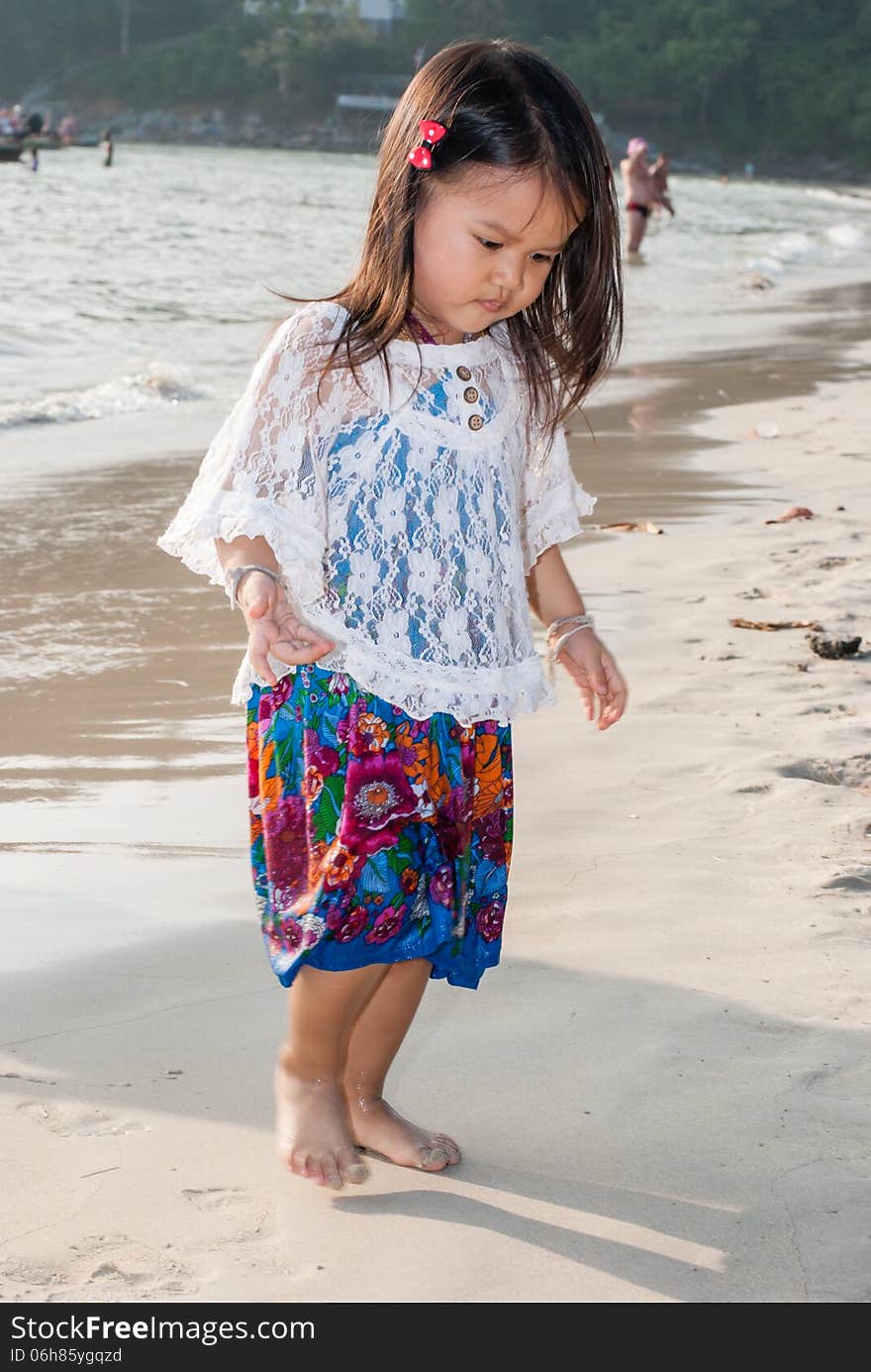 Backview of a caucasian white girl child with long blond hair standing and playing in the water of the Phuket on a beach in Thailand during summer holidays. Backview of a caucasian white girl child with long blond hair standing and playing in the water of the Phuket on a beach in Thailand during summer holidays.