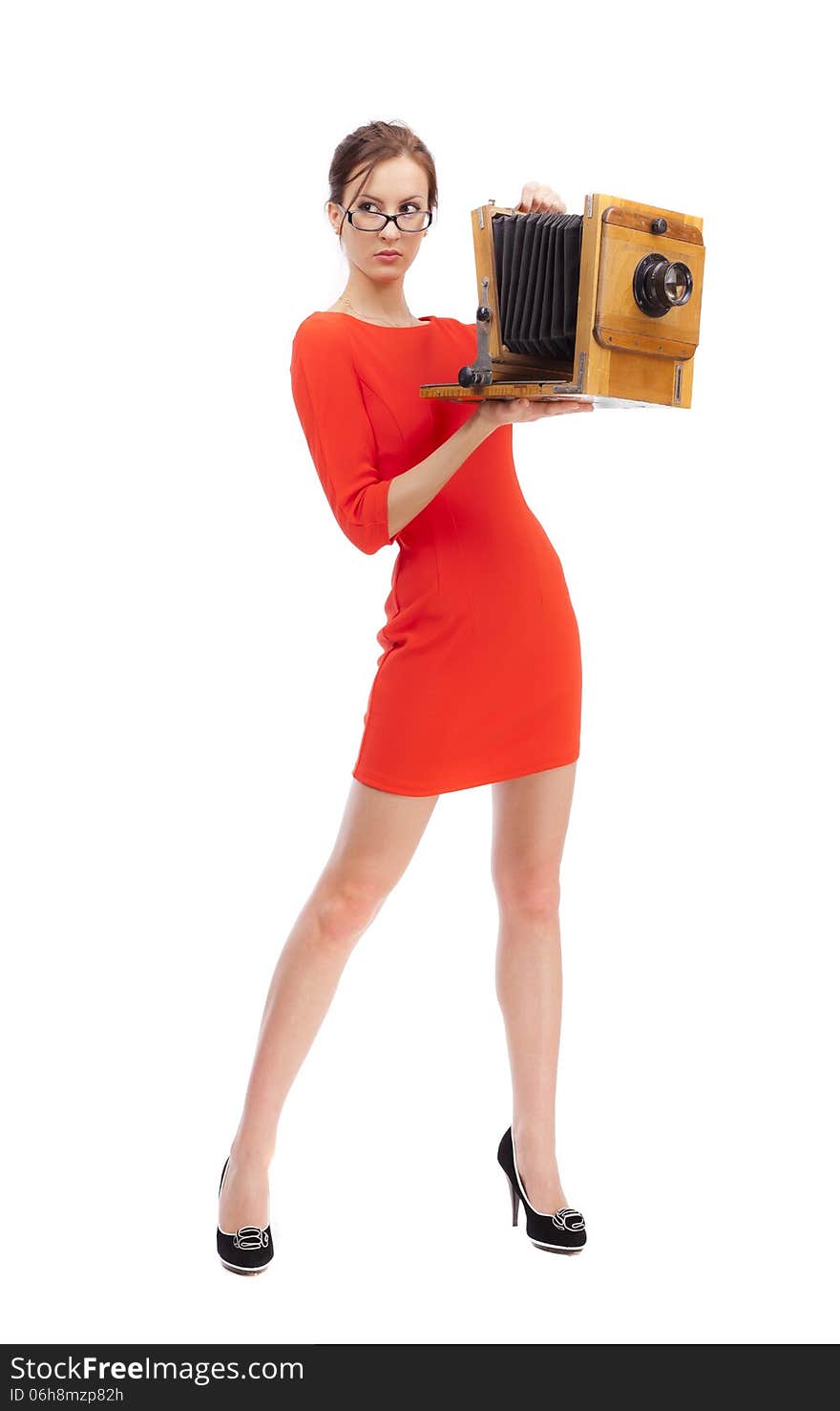 Girl in red dress with an old camera on a white background