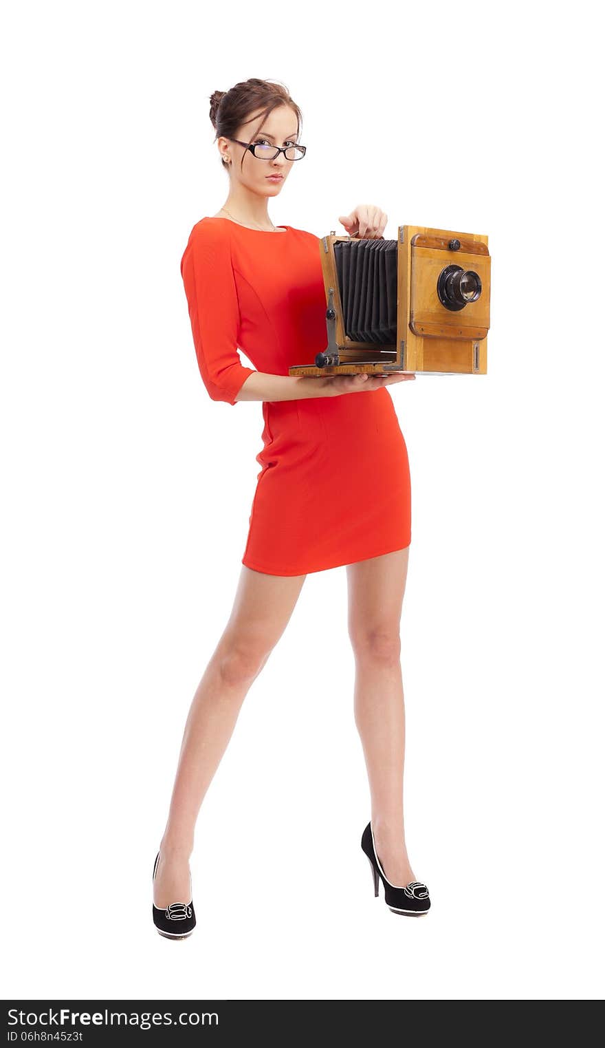 Girl in red dress with an old camera on a white background