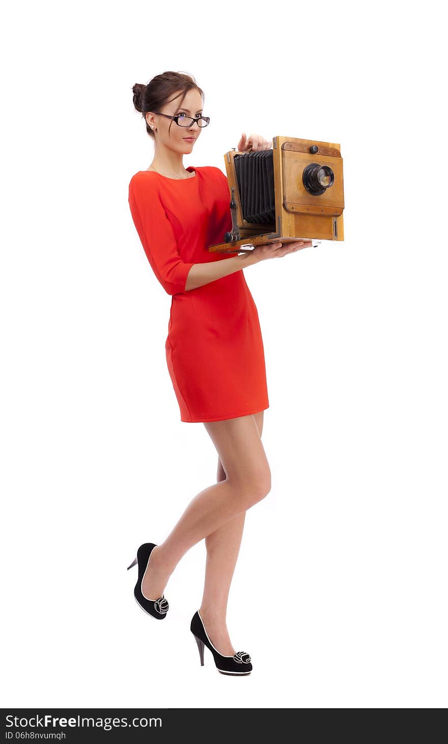 Girl in red dress with an old camera on a white background