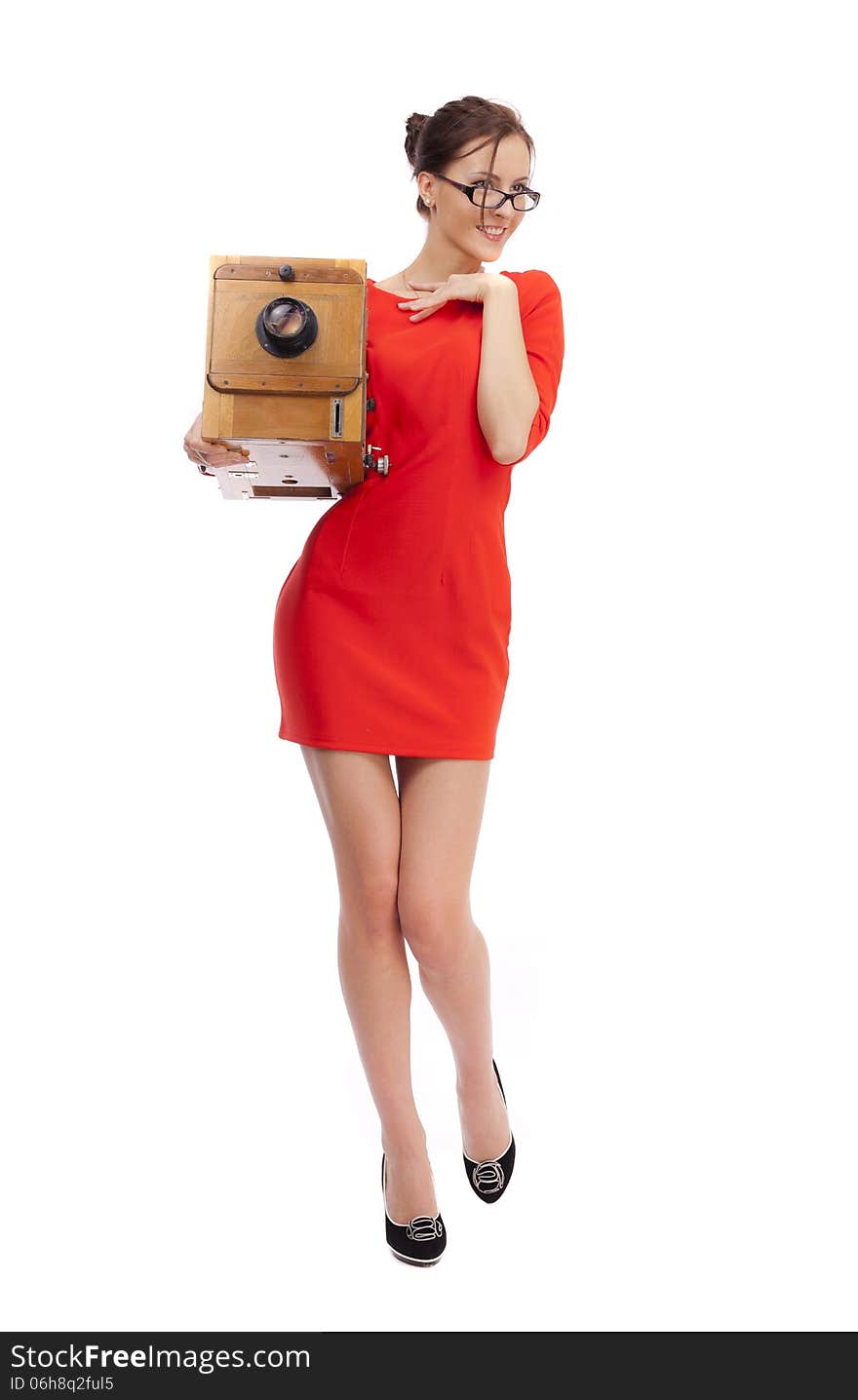 Girl in red dress with an old camera on a white background