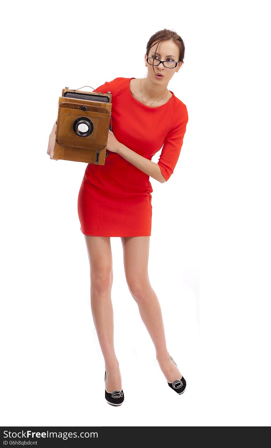 Girl in red dress with an old camera on a white background