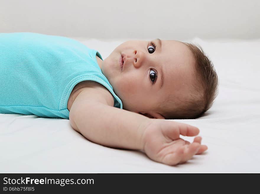 Baby boy laying on bed, white background