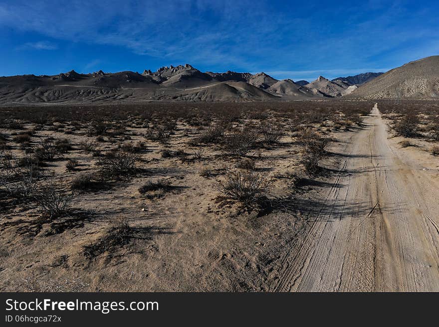 Dirt Road Leads To Mountains Through Desert