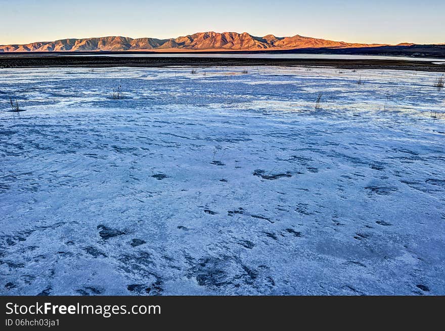 Ice and snow over a lake with sunny mountains in the background. Ice and snow over a lake with sunny mountains in the background