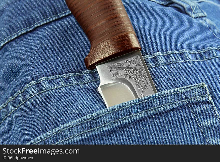 Knife with a brown handle and engraved in the jeans pocket. Knife with a brown handle and engraved in the jeans pocket