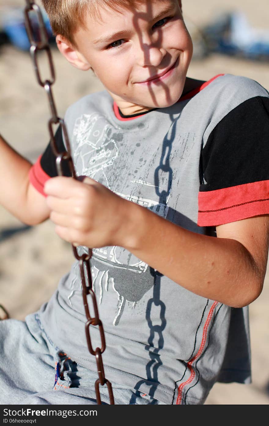 Smiling boy on the swing looking in the camera, portrait