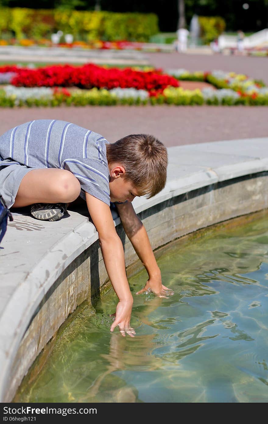 Little boy putting his hands into the water in the pond, summer day. Little boy putting his hands into the water in the pond, summer day