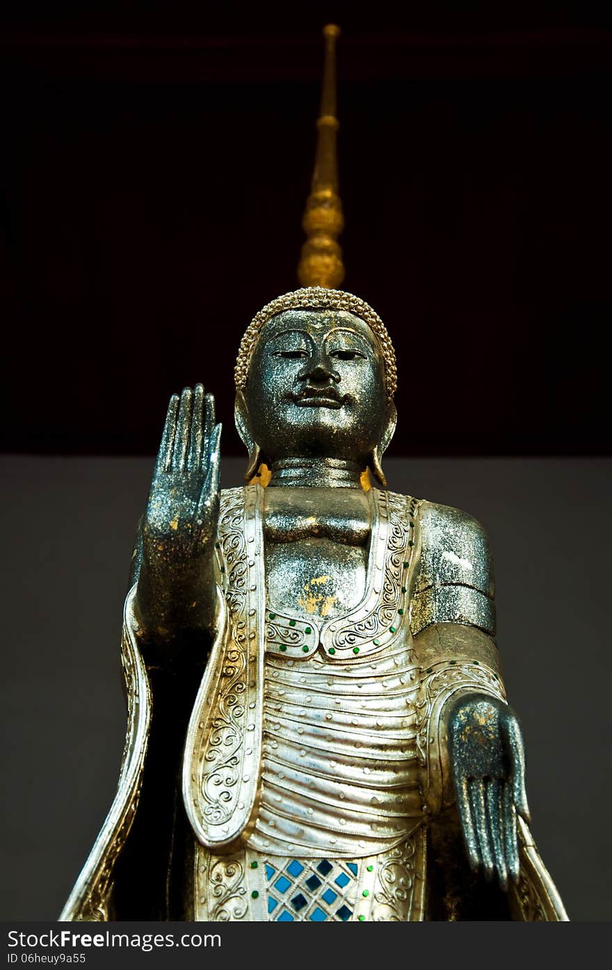 The metal standing Buddha with golden pagoda in the temple in Th