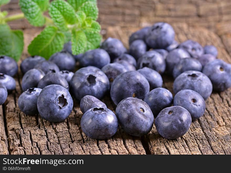 Fresh blueberries with mint leaves on a wooden background