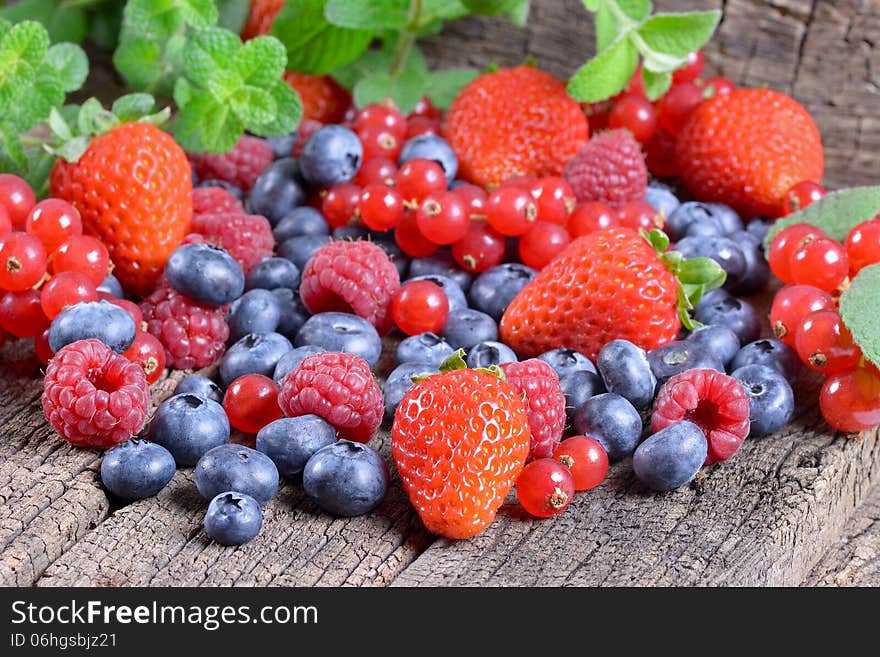 Fresh berries with mint leaves on a wooden background. Fresh berries with mint leaves on a wooden background