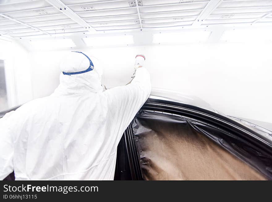 Automotive industry - engineer painting and working on a black body of a car