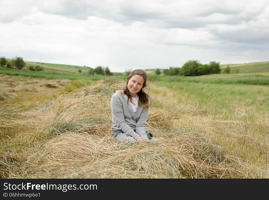 Girl in hay  with clouds