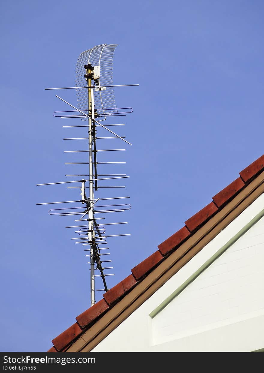 Tv antenna on red roof of house in sunny day. Tv antenna on red roof of house in sunny day