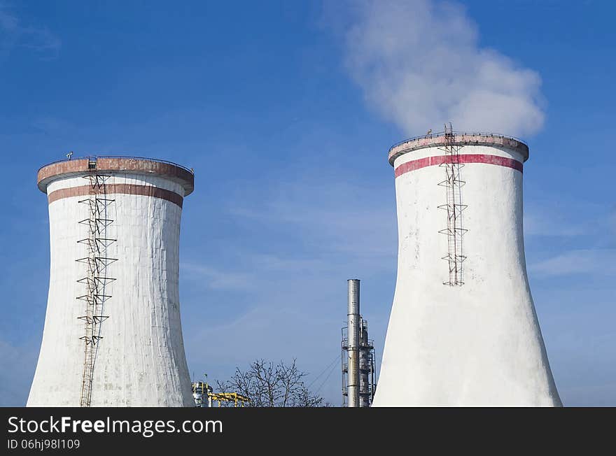 Two white cooling towers and petrochemical installations in the background. Two white cooling towers and petrochemical installations in the background